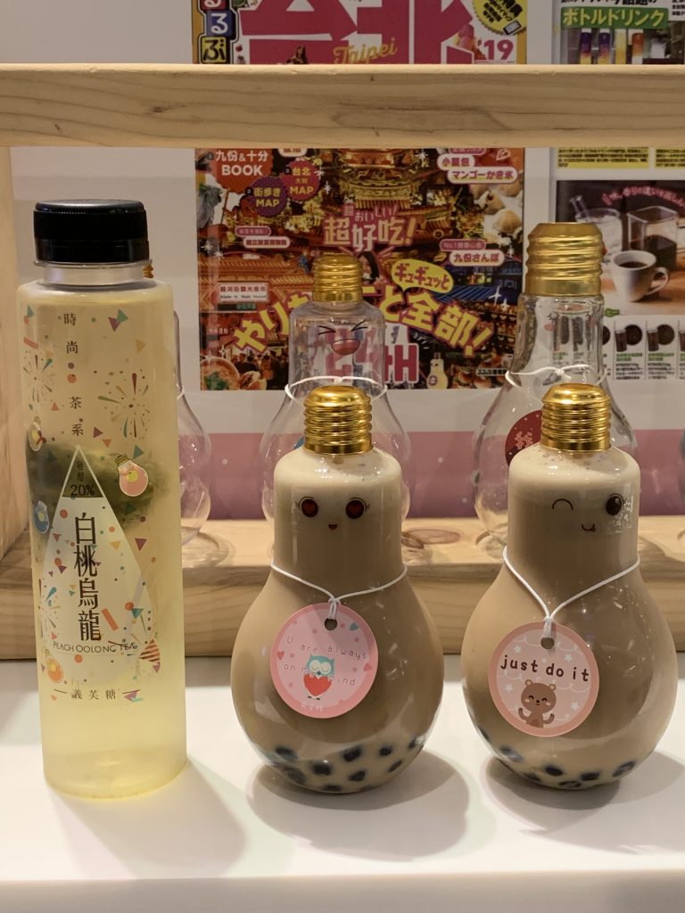 Two light bulb containers filled with milk tea and tapioca pearls.