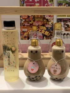 Two light bulb containers filled with milk tea and tapioca pearls.